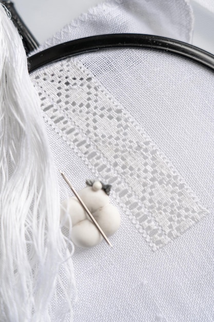 Manos bordando sobre tela blanca